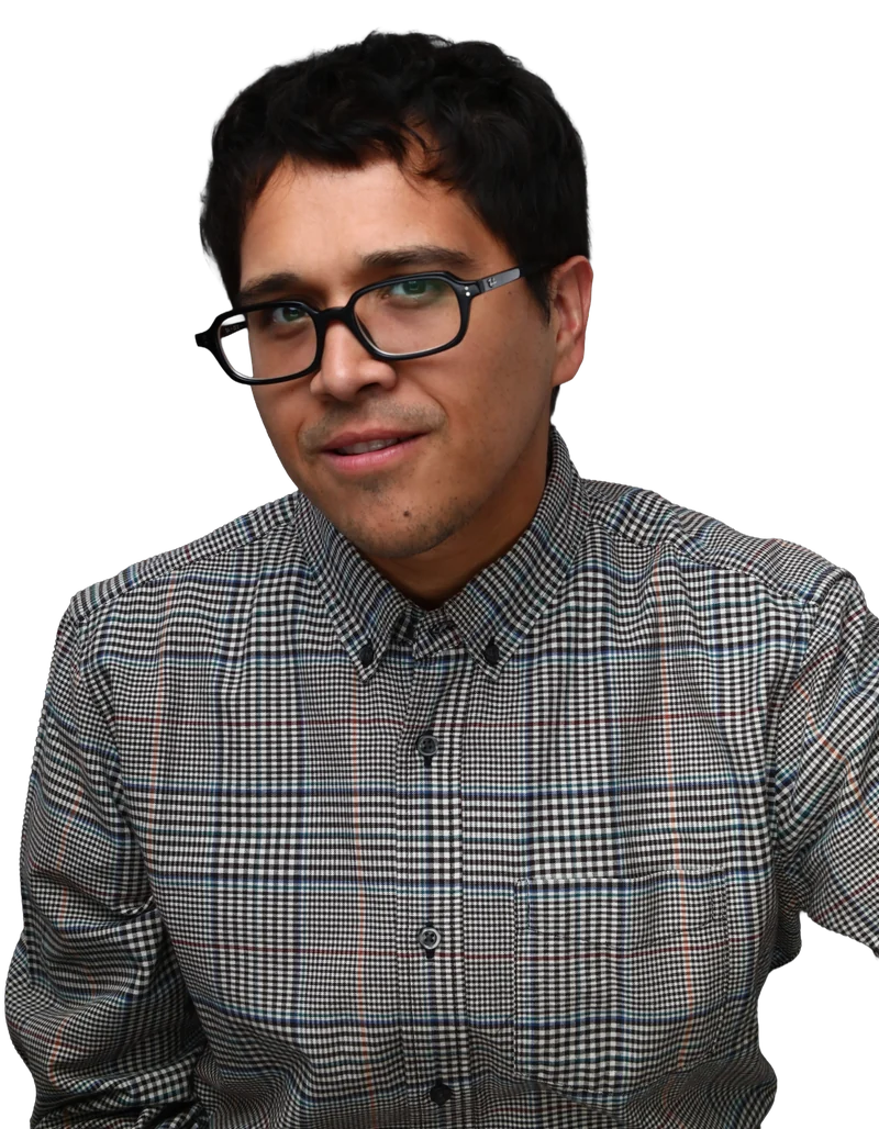 Nick Ciriano smiling in a plaid button-down shirt and black glasses