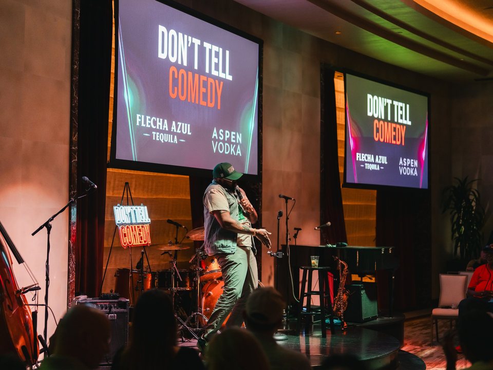 A comedian performs on stage at Nowhere Lounge inside Fontainebleau Las Vegas, with Don't Tell Comedy screens and a neon sign